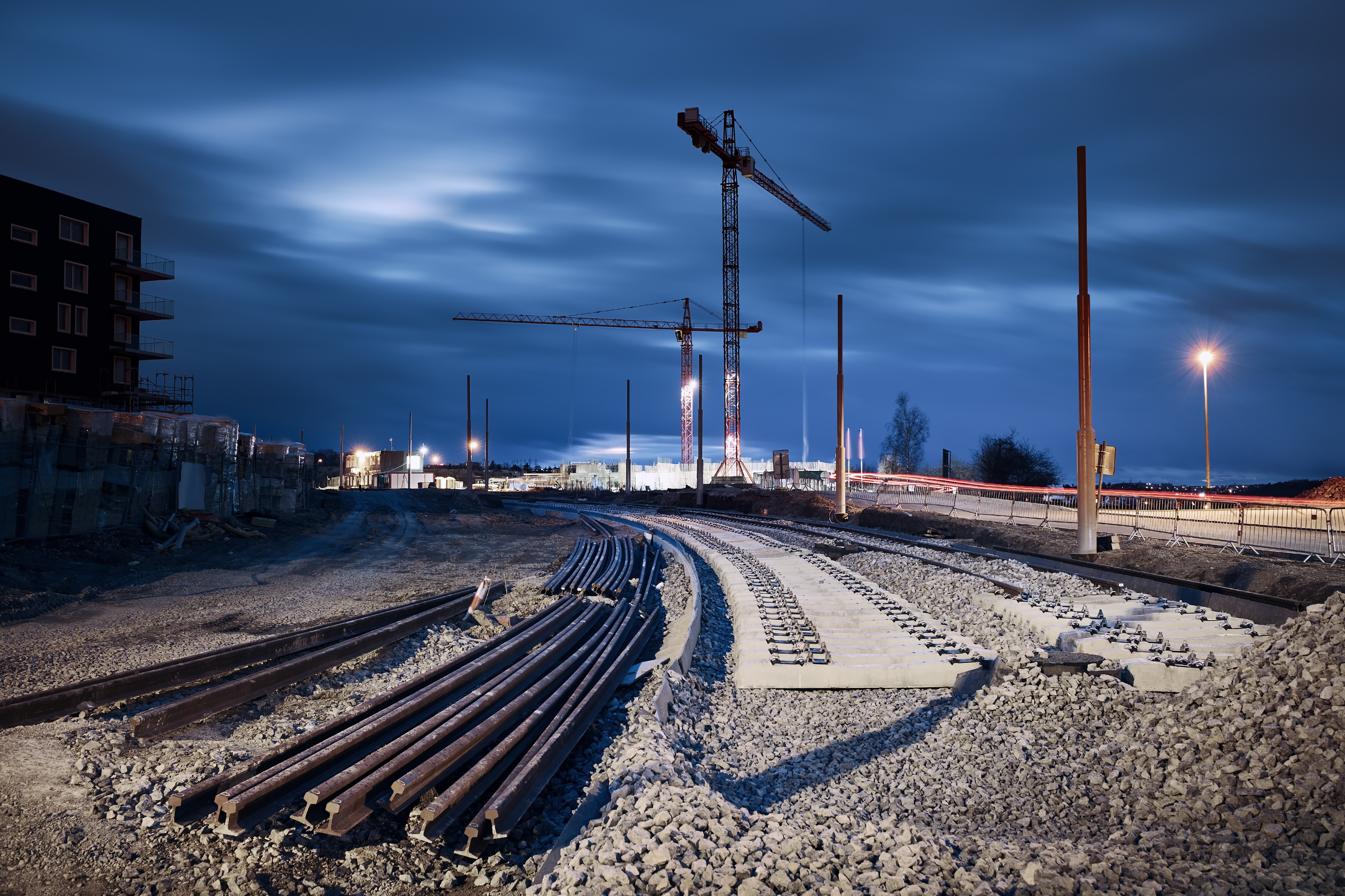 Chantier ferroviaire nocturne — pose de voie avec grues